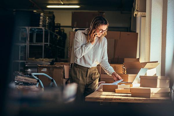 Mujer sonriente propietaria de e-commerce rodeada de paquetes