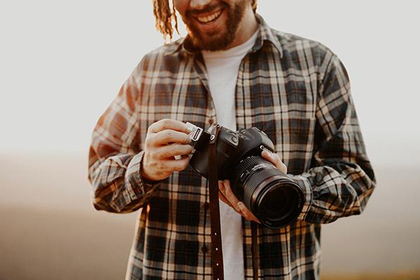 Hombre joven y sonriente sosteniendo su cámara