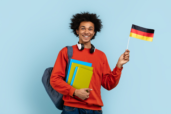Estudiante de alemán con una banderita de Alemania, mochila y libros con un fondo azul