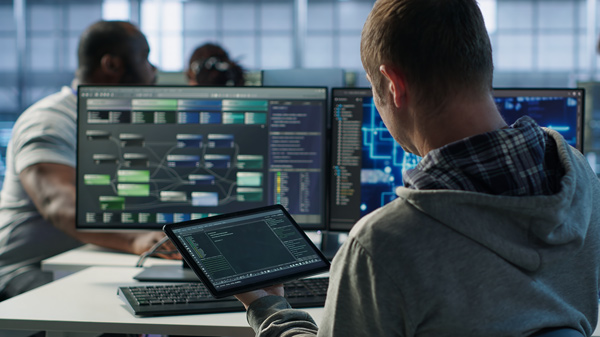 Programador con varias pantallas de ordenador y tablet analiza mapas de relaciones