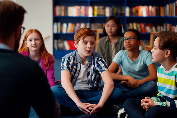 El Debate como herramienta de aplicación del cine en el aula Grupo de alumnos jóvenes con una biblioteca al fondo debate sobre una película