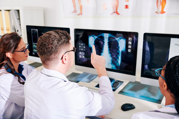 Grupo de médicos viendo radiografías en varias pantallas de ordenador