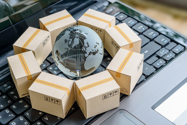 imagen alegórica de comercio internacional con una bola del mundo, cajas y ordenador portátil