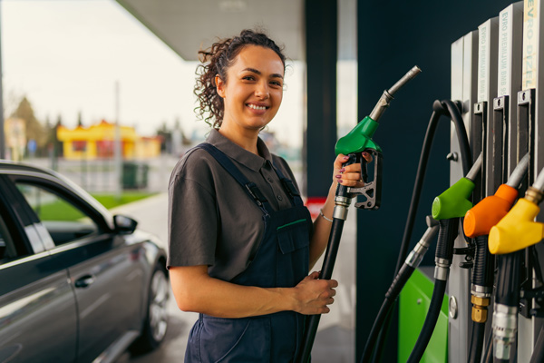 Mujer trabajando en una gasolinera poniendo combustible
