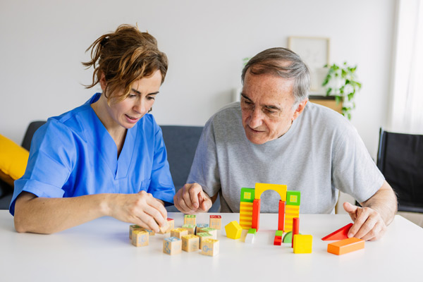 Cuidadora estimulando a un paciente con demencia con un juego de piezas de construcción