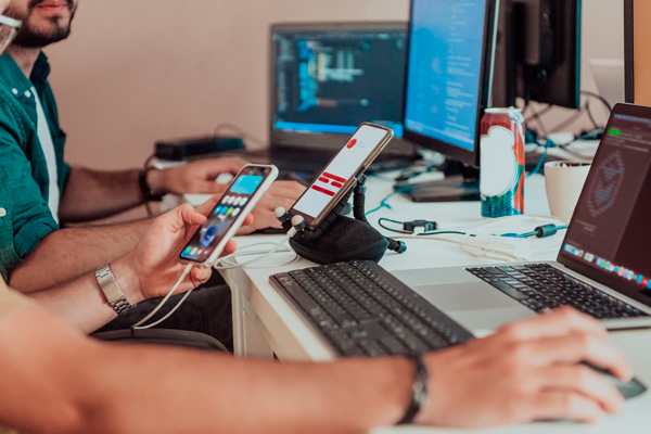 desarrolladores trabajando con portátiles y móviles en aplicaciones para móvil