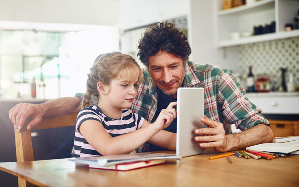 Un padre trata las dificultades de aprendizaje de su hija pequeña con una tablet