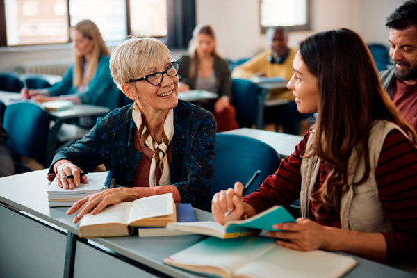 Dos mujeres en aprendizaje permanente, una mayor de pelo corto, rubia y gafas la otra joven, morena y de pelo largo durante una clase