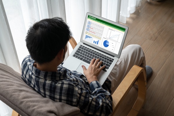 Excel Avanzado persona en un sofá con un portatil en las rodillas, trabaja en un excel