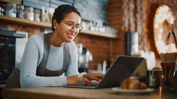 Empresaria de hostelería trabajando en la gestión de su bar cafetería en un portátil