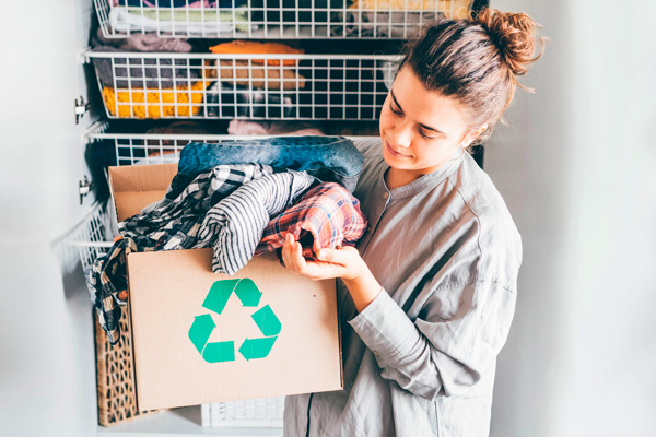 mujer joven con una caja de cartón con ropa para reutilizar
