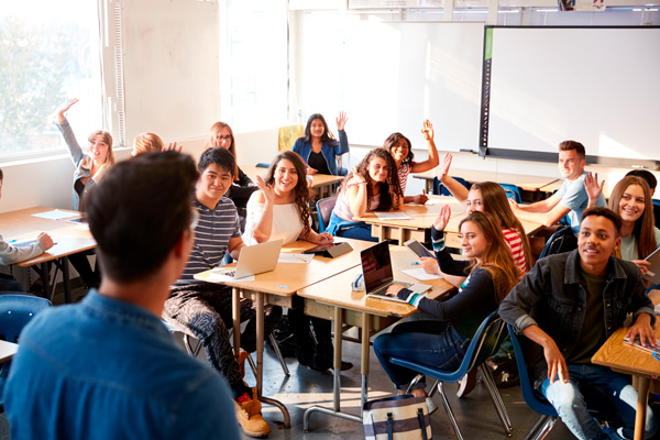 aula con adolescente y la mano levantando para participar en la clase