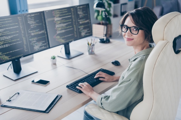 Programadora trabajando con código en dos pantallas