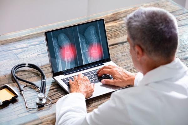 médico revisando radiografías digitales en portátil