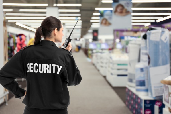 mujer con coleta e identificación como vigilante de seguridad en el uniforme hace una ronda por un centro comercial