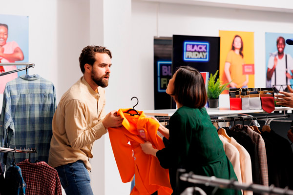 dos personas en una tienda luchando por una prenda naranja durante el black friday