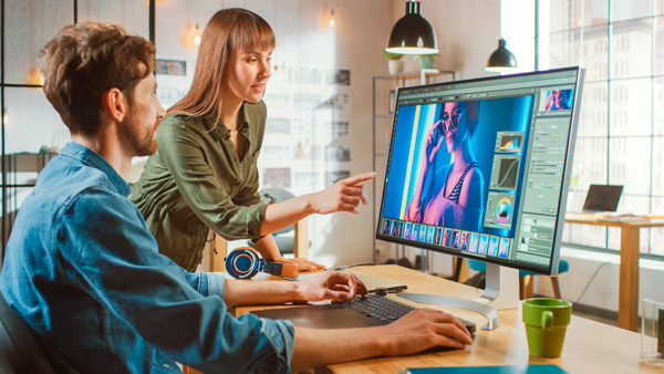 Dos diseñadores retocando una imagen con photoshop en un ordenador de escritorio