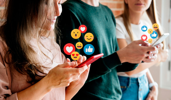 tres chicos interactuando en redes sociales en el móvil, se ven iconos de interacción saliendo de los teléfonos