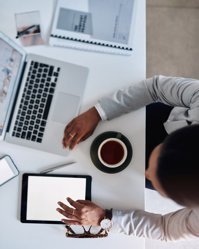 Toma cenital de un hombre trabajando en un escritorio con tablet, móvil y portátil para buscar empleo en redes sociales