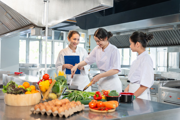 Aprendiendo técnicas de cocina Profesora con dos alumnas de tecnicas culinarias en una cocina profesional