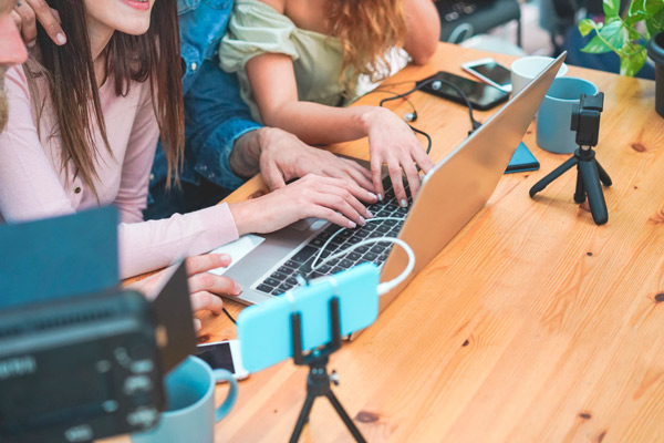 Grupo de personas editando un vídeo en un portátil que bajan desde un móvil