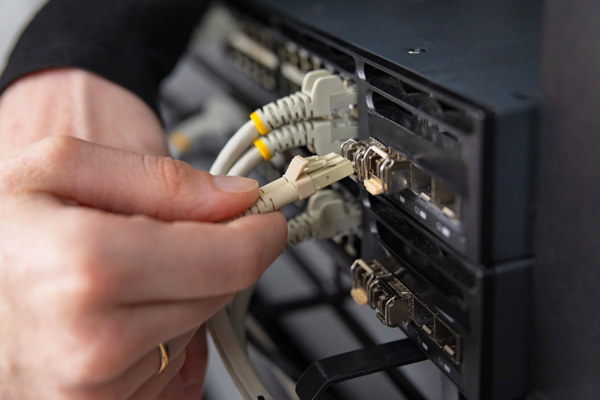Manos de mujer conectando un cable de red a un servidor