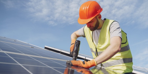 Chico instalando paneles solares con la ayuda de un taladro 