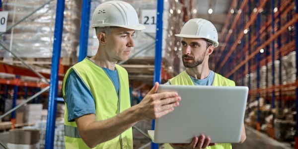 trabajadores de almacén revisando información en portatil para verificar las existencias 