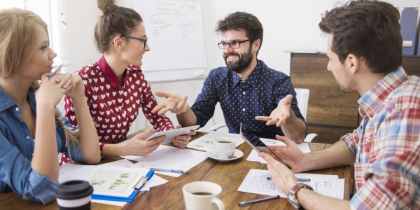 reunión de jóvenes empleados en una mesa con café y muchos papeles